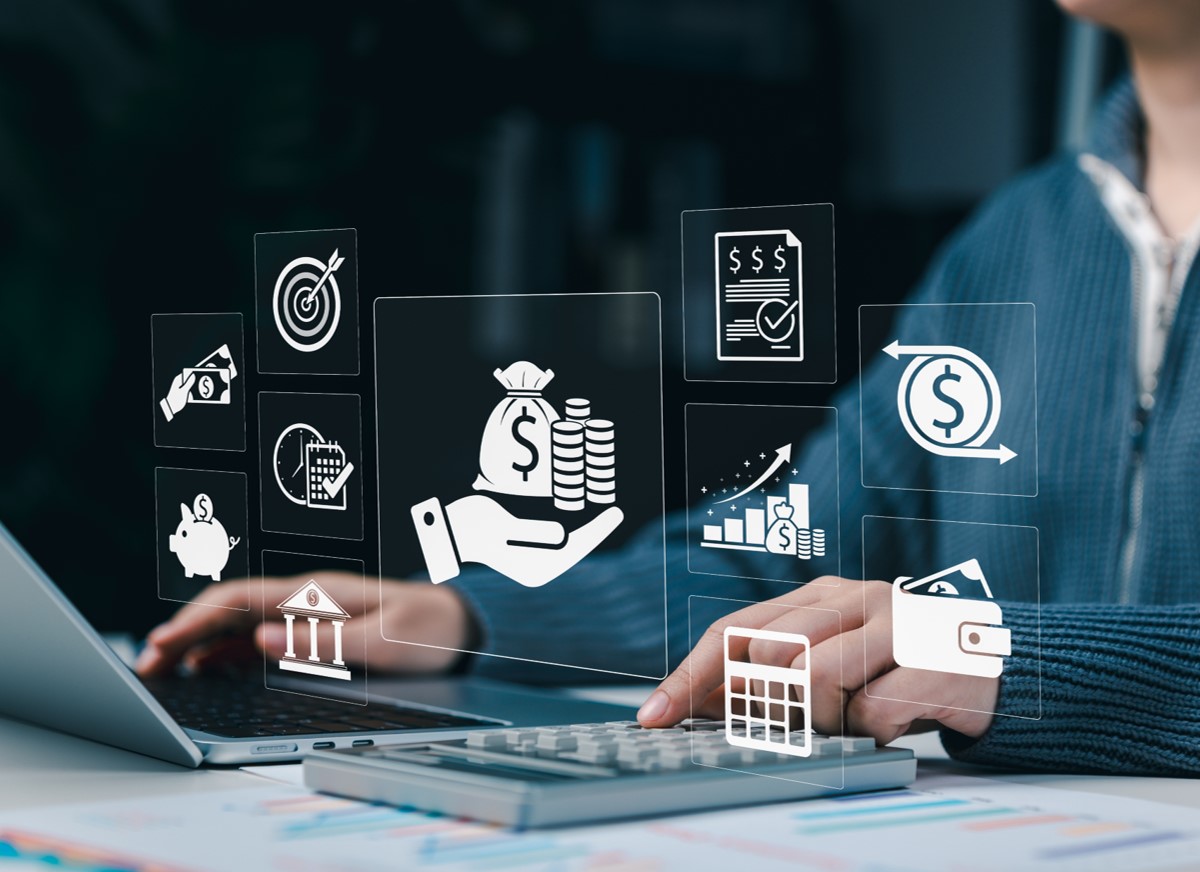 Executiva usando o notebook e alguns ícones remetendo a finanaças em primeiro plano na imagem