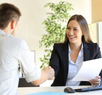 Homem apertando a mão de uma mulher em uma entrevista de trabalho.