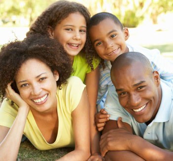 Família feliz composta por um homem, uma mulher, e duas crianças, um menino e uma menina.