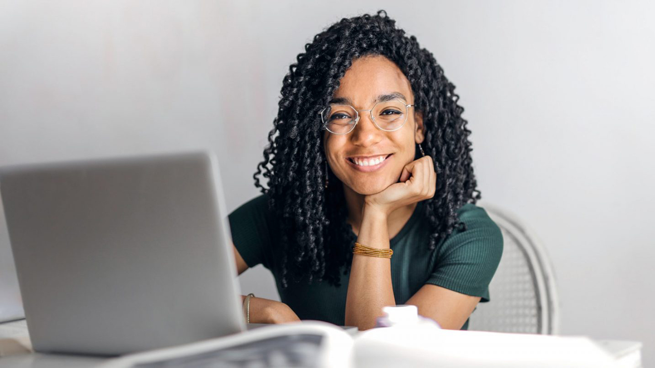 Aluna sorridente diante de um notebook