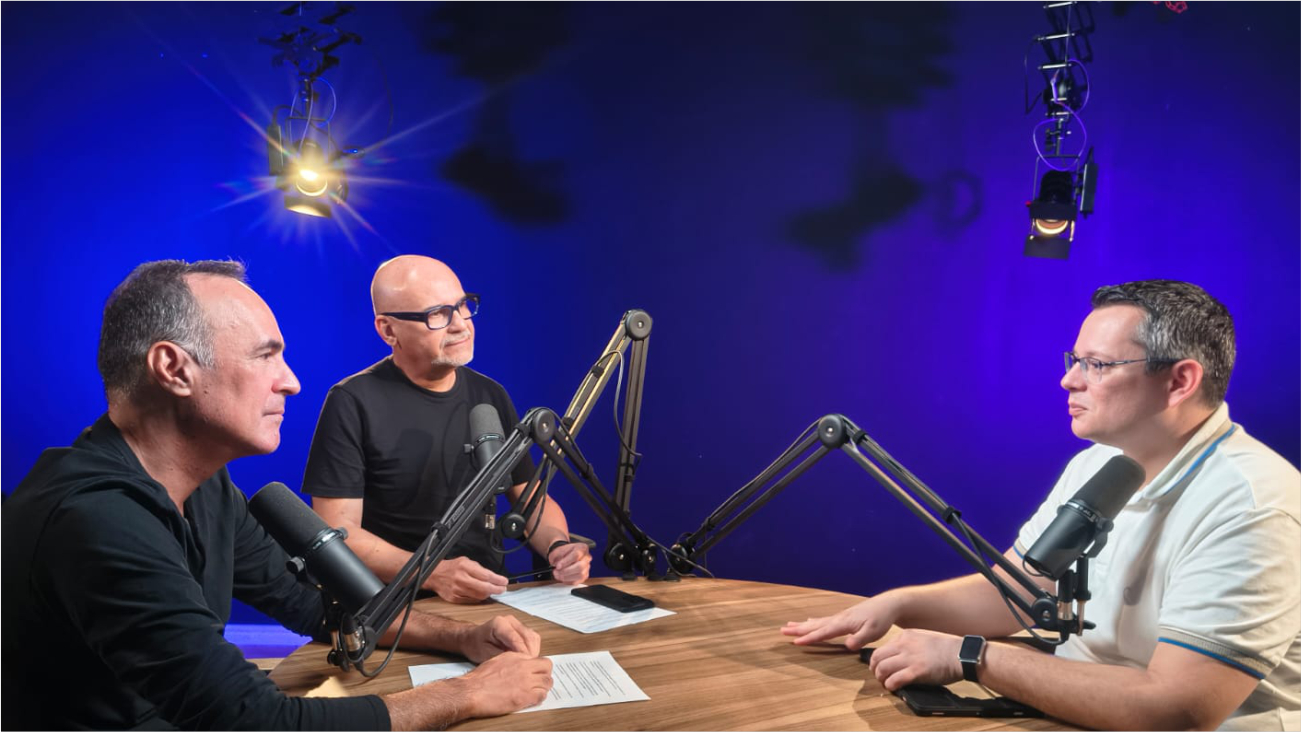 Três homens em mesa de entrevista
