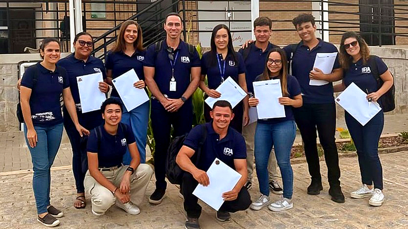 Equipe da Indústria Piloto de Alimentos da UFCG posa em frente a um prédio, usando camisas institucionais e segurando documentos.