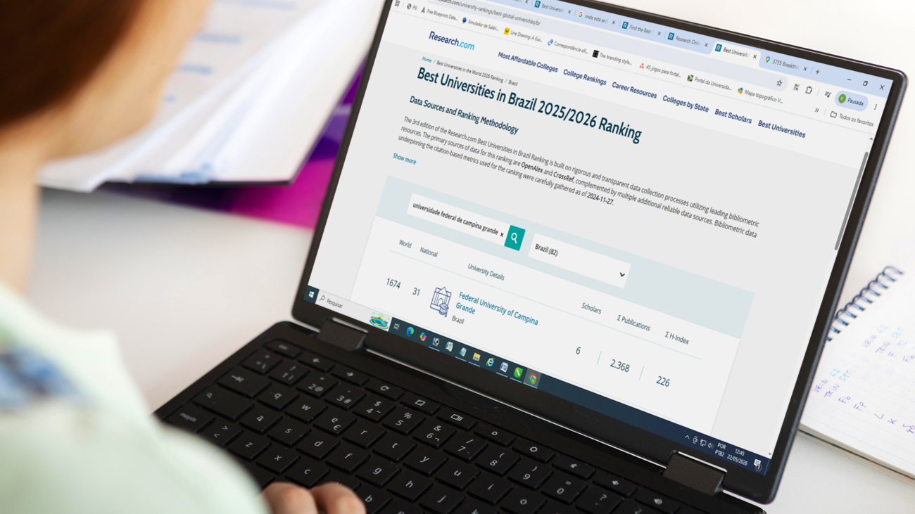 Pessoa usando um notebook para acessar uma página da Research.com com o ranking “Best Universities in Brazil 2025/2026”, exibindo informações sobre universidades brasileiras e indicadores acadêmicos.