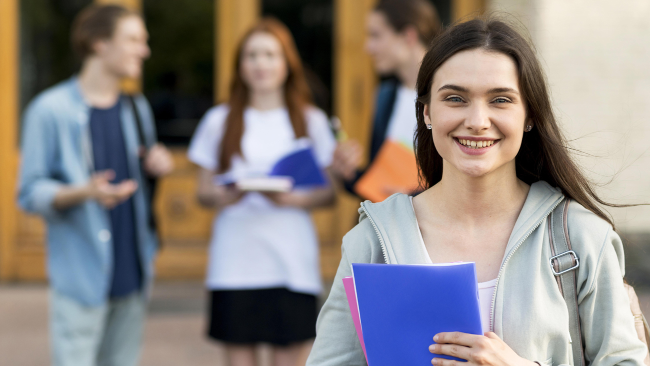 Aluna sorridente tendo ao fundo três estudantes conversando