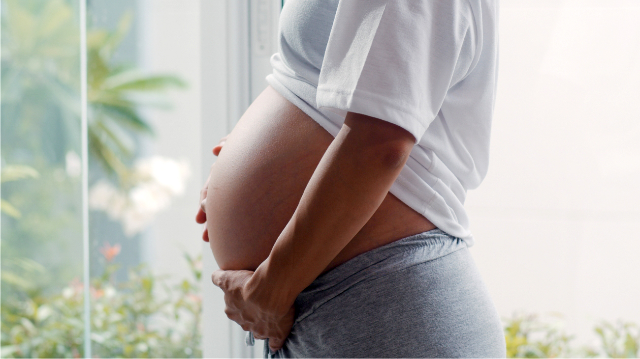 Imagem de uma mulher grávida de perfil segurando a barriga